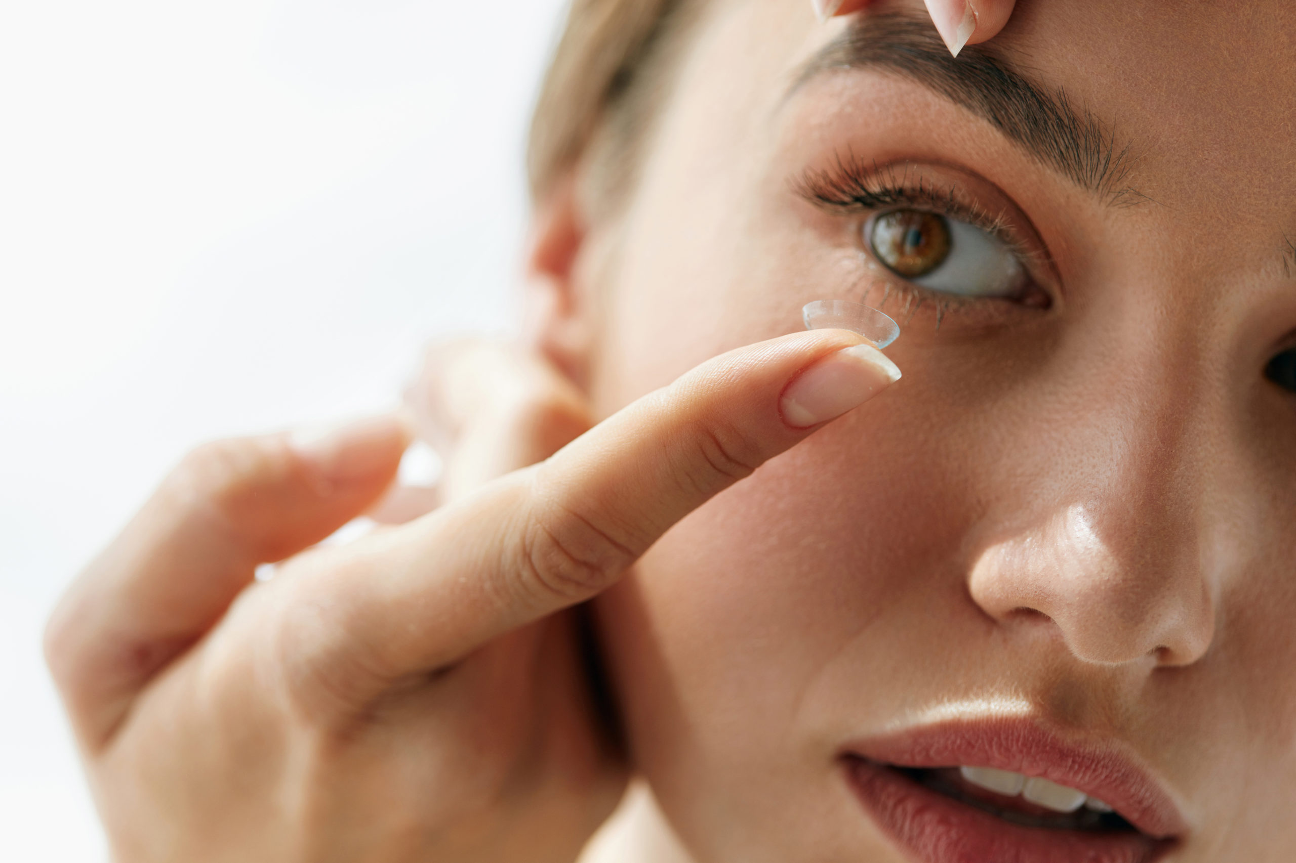 young woman inserting contact lens into eye