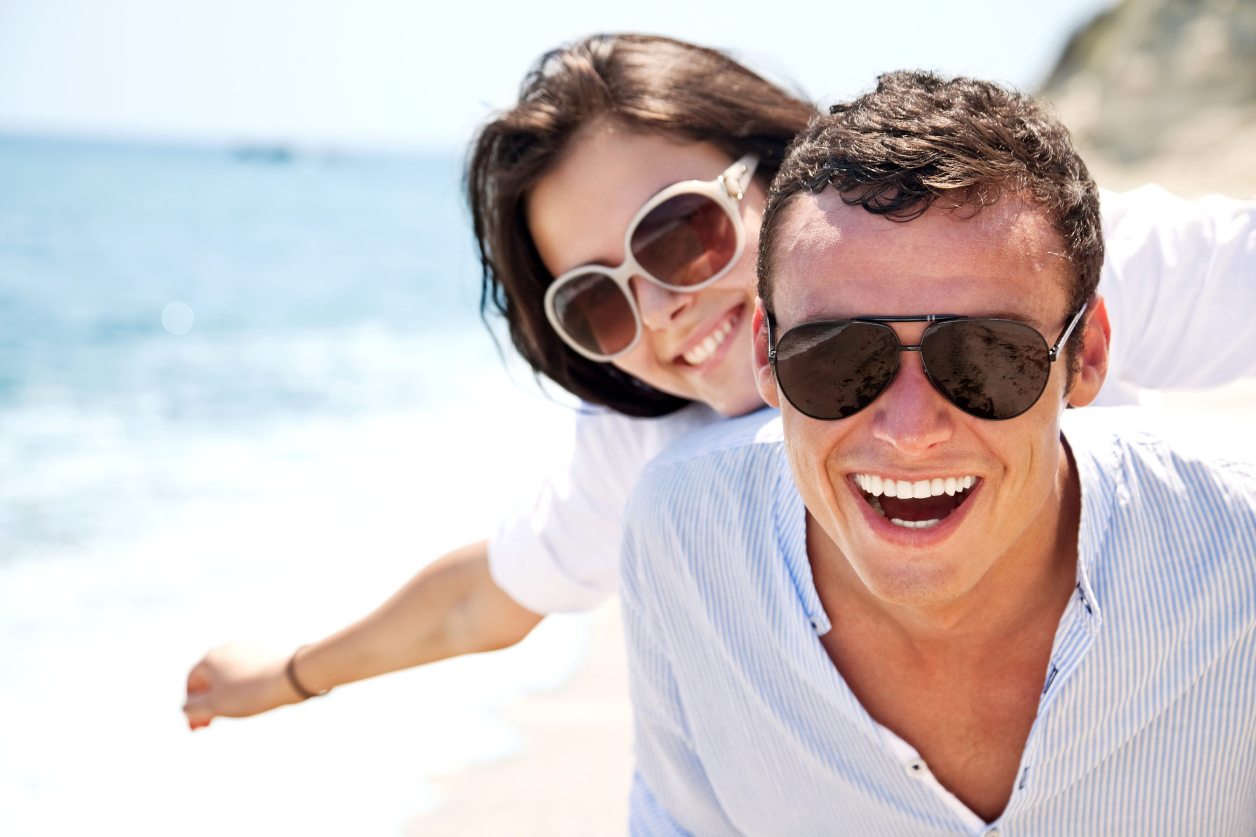 happy couple on beach wearing sunglasses