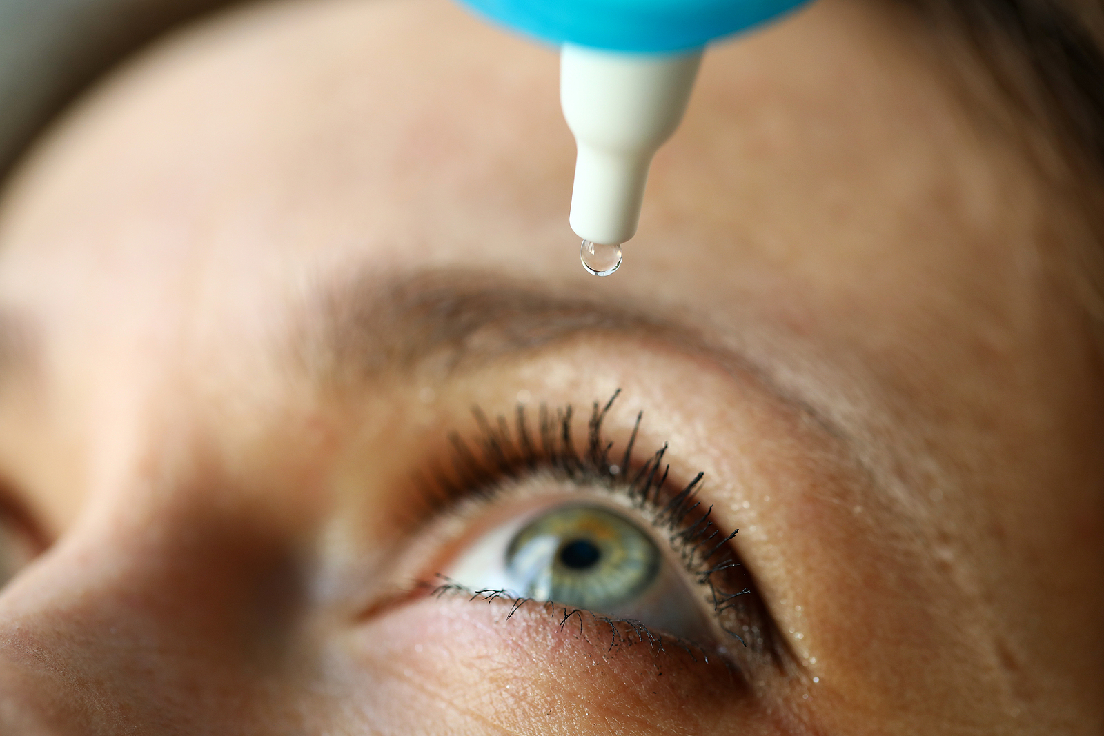 close up of woman putting in eye drops