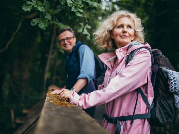 Older couple in windbreakers on a hike in forested area