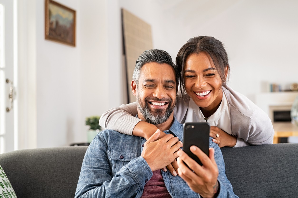 happy-indian-couple-looking-at-cell-phone